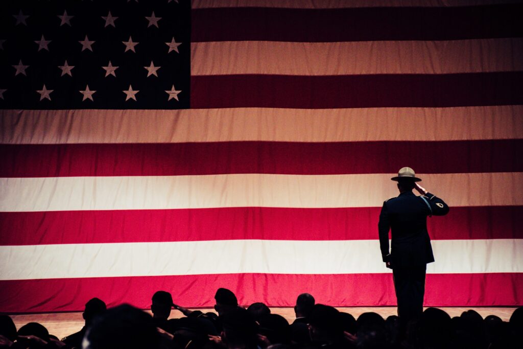 men in uniform saluting a large American flag